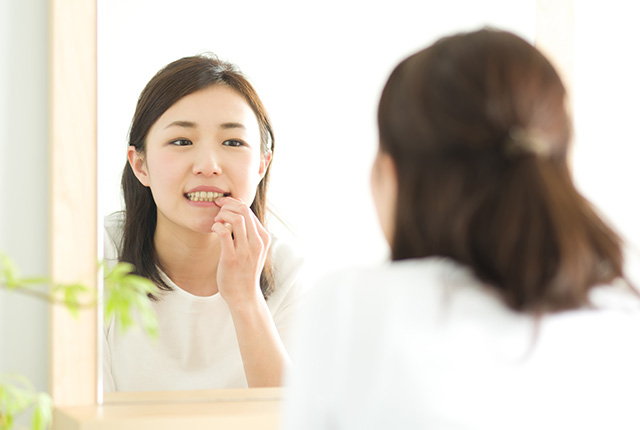 鏡で自分の歯を見る女性